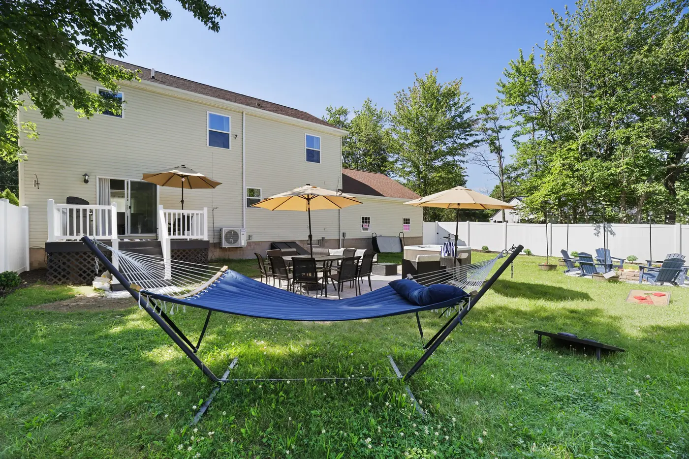 The fenced backyard at 106 Greenleaf Drive in Long Pond, with a hammock, patio seating and umbrellas