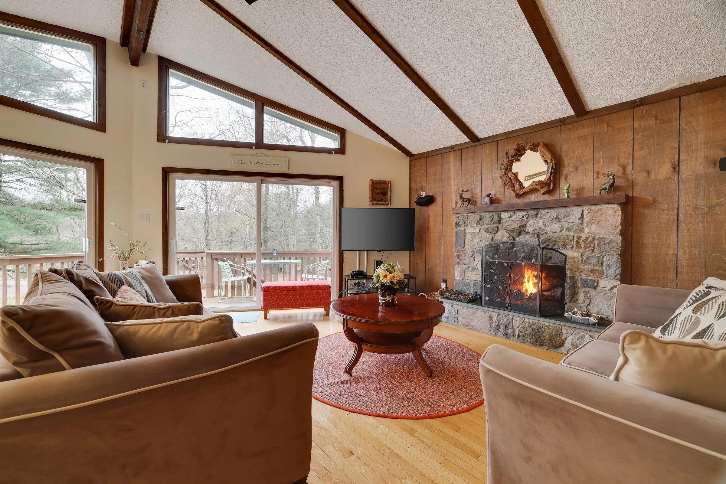 The great room at 148 Pineknoll in Lake Harmony, with a lit stone fireplace and vaulted ceiling