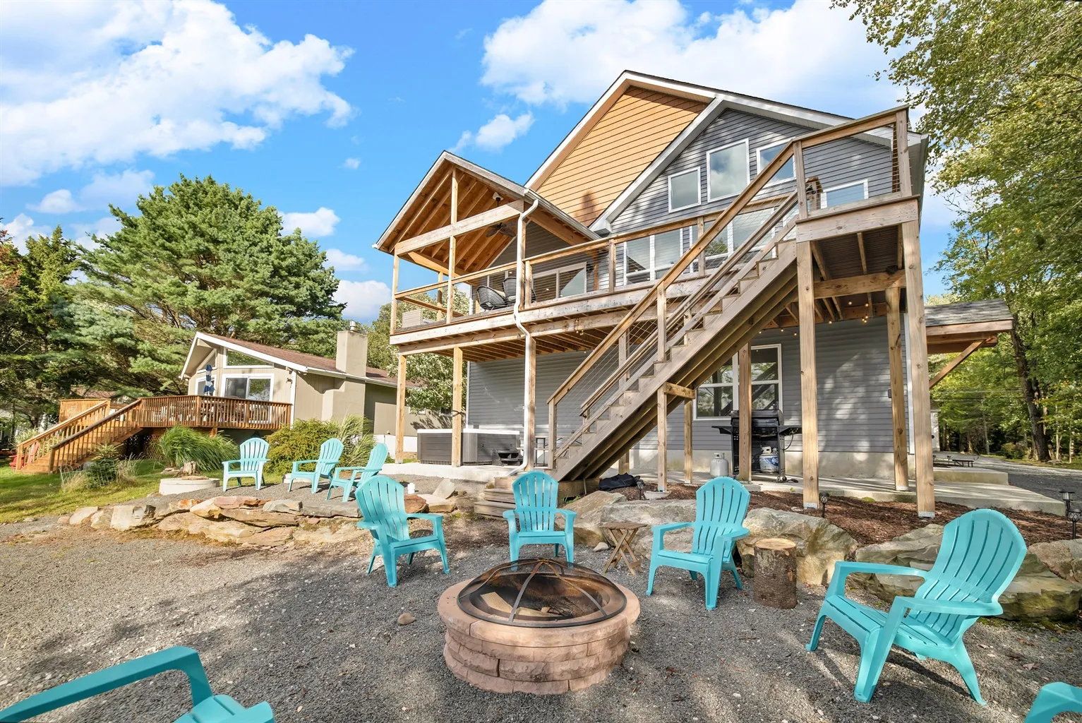 The back of a lakefront home at Arrowhead Lake, with its deck, fire pit and Adirondack chairs