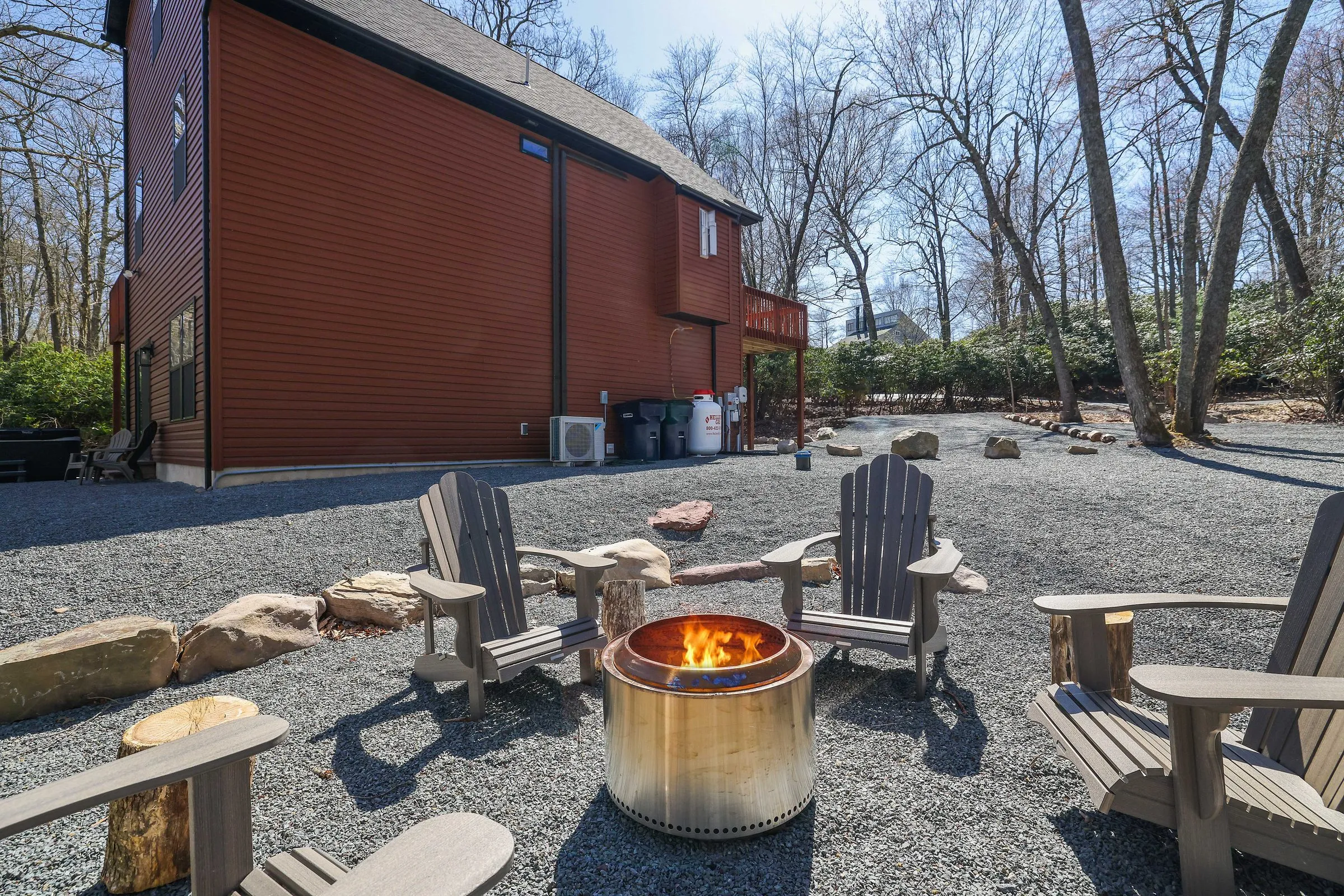 A fire pit and Adirondack chairs beside The Cedar & Stone Lodge, a home Ideal manages in Lake Harmony
