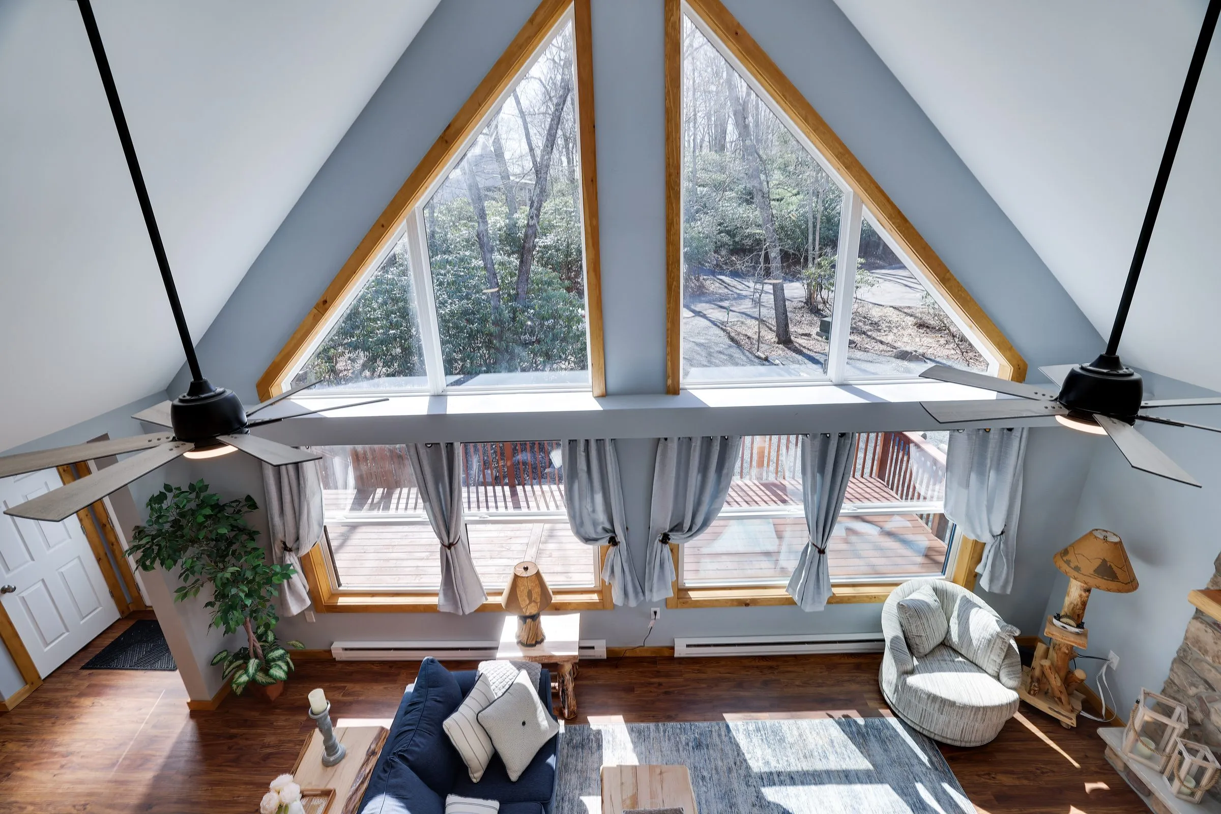 The A-frame great room at The Cedar & Stone Lodge, a home Ideal manages in Lake Harmony, with triangular windows over the deck