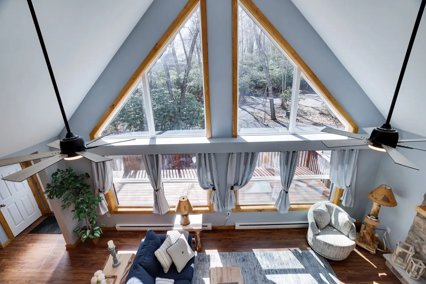 The A-frame great room at The Cedar & Stone Lodge, a home Ideal manages in Lake Harmony, with triangular windows over the deck